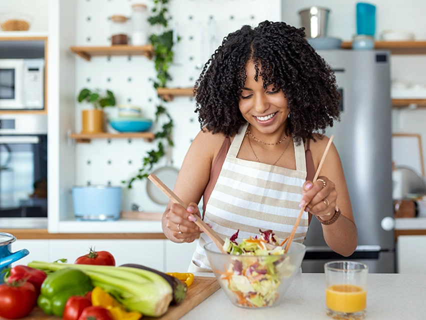 A woman making a salad in the kitchen.