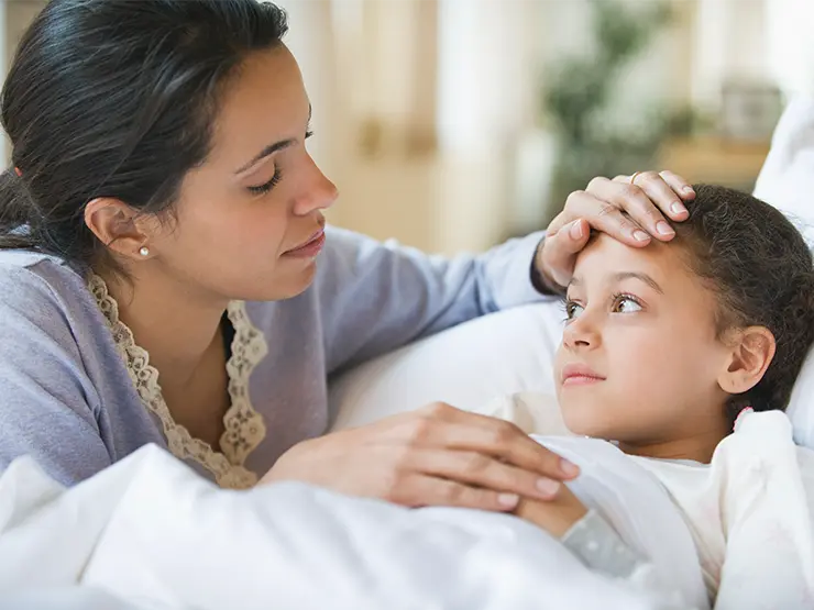 image of mom looking at child in bed with hand on forehead