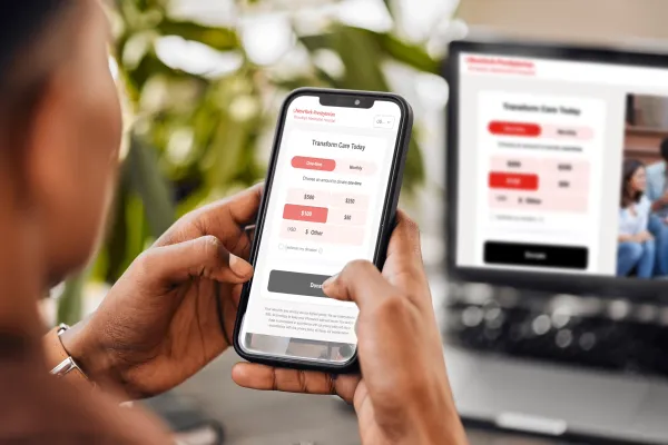 a person working on a laptop and reviewing page on their phone